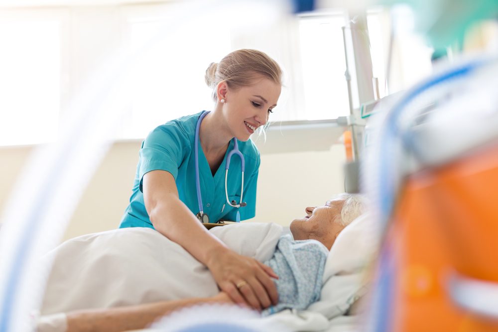 Nurse in scrubs walking through a hospital corridor under fluorescent lights at night