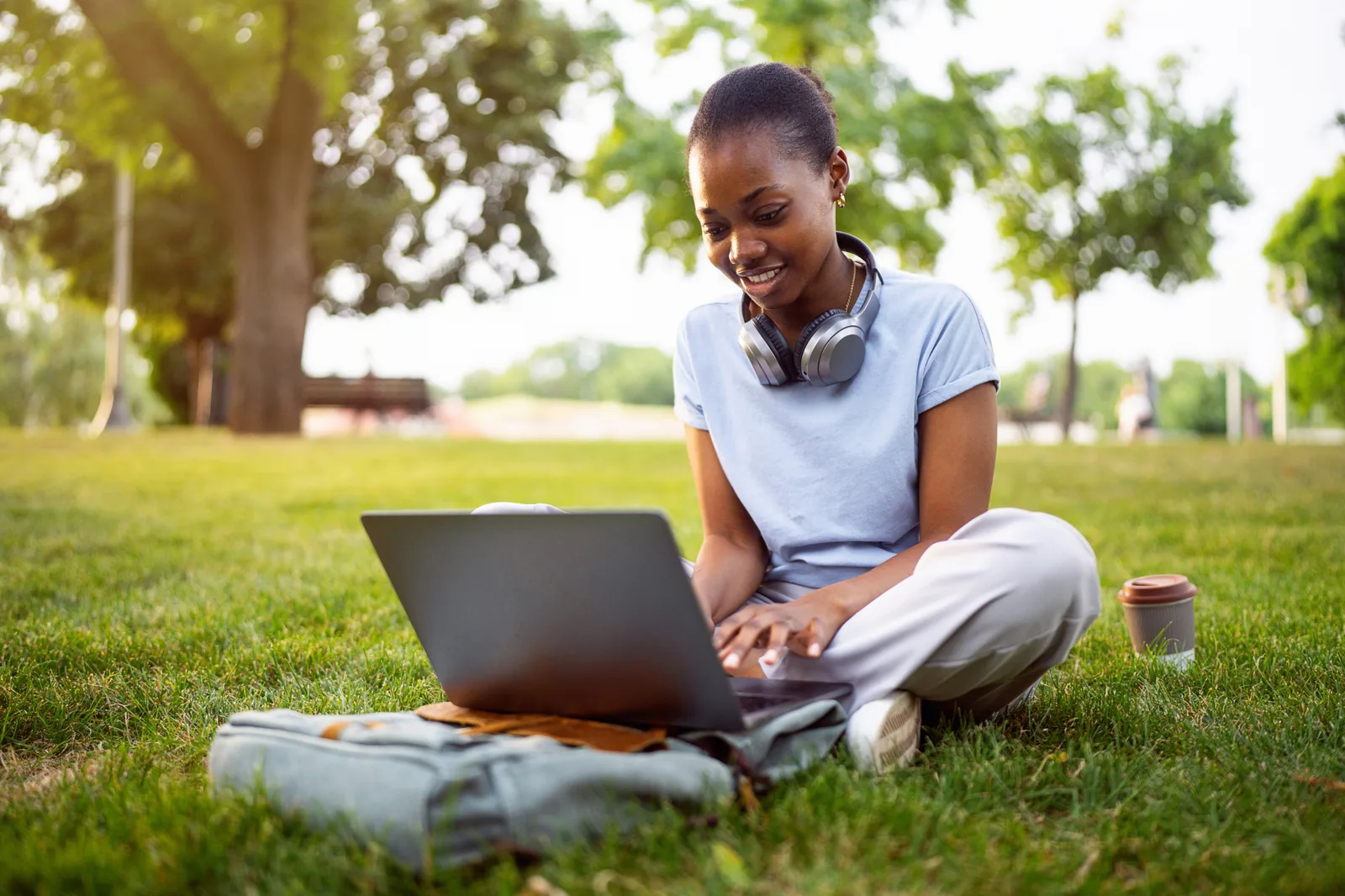 A university student reviewing her health plan details on a laptop in a campus common area, backpack beside her.