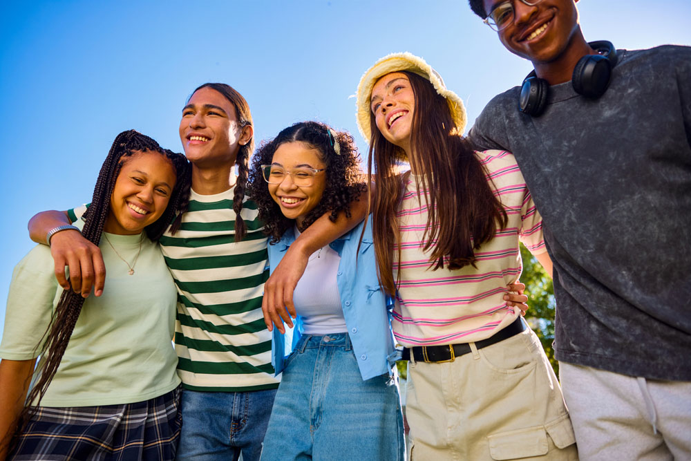 A group of smiling teens standing outdoors with arms around each other, symbolizing confidence, friendship, and social support for ADHD teens.