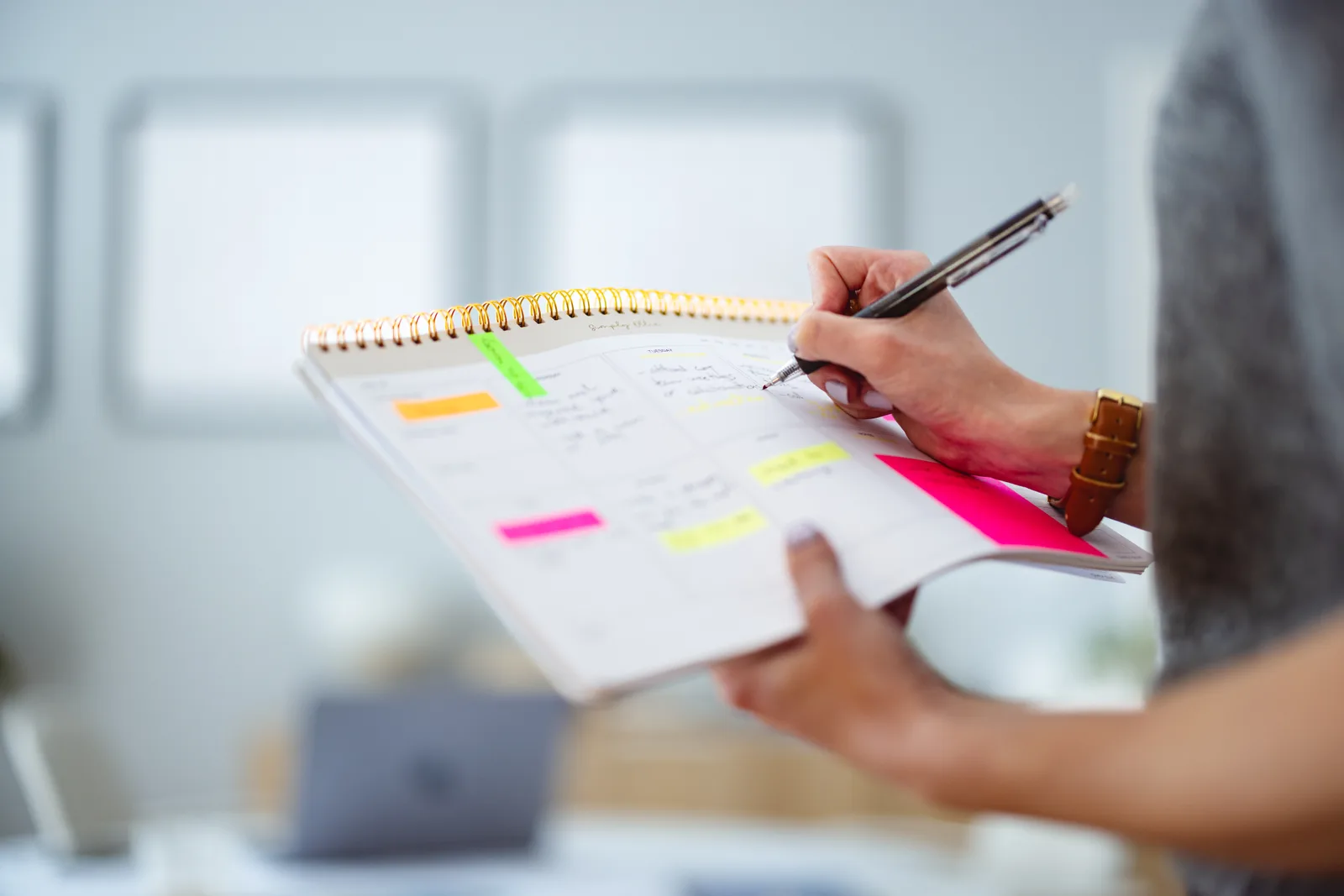 Woman marking progress in a paper planner at a bright home desk, illustrating week-by-week tracking of ADHD treatment goals.