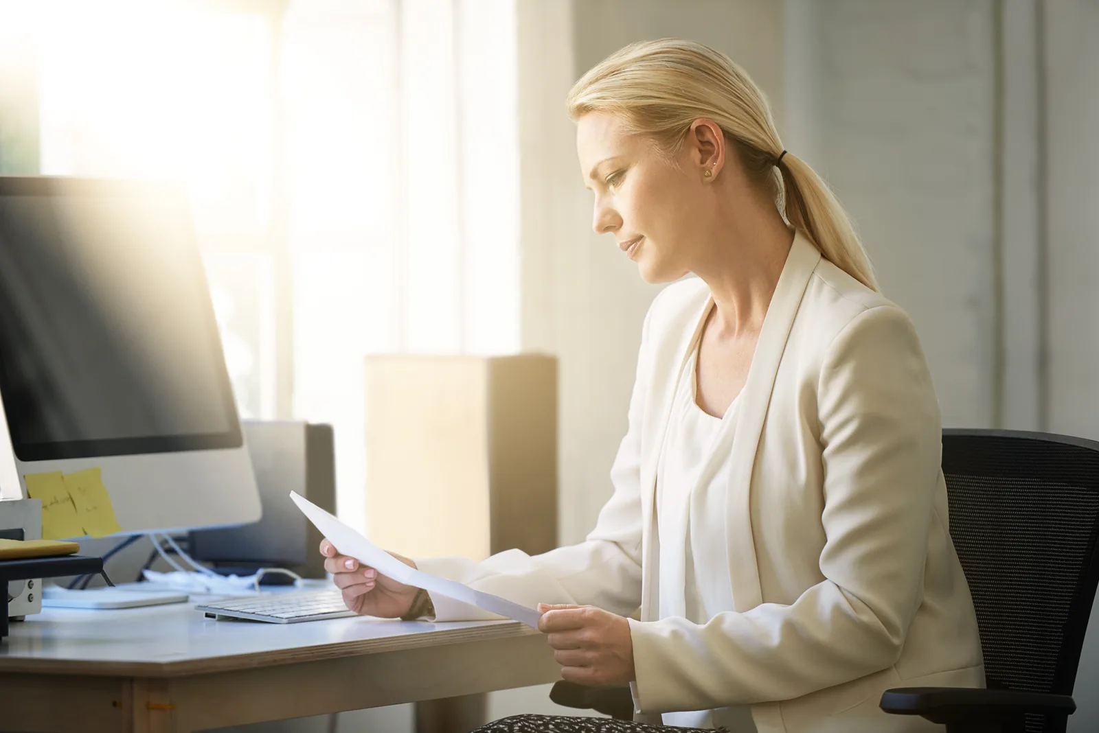 Professional reviewing her workplace benefits booklet at an office desk, planning how to use employer coverage for ADHD support.