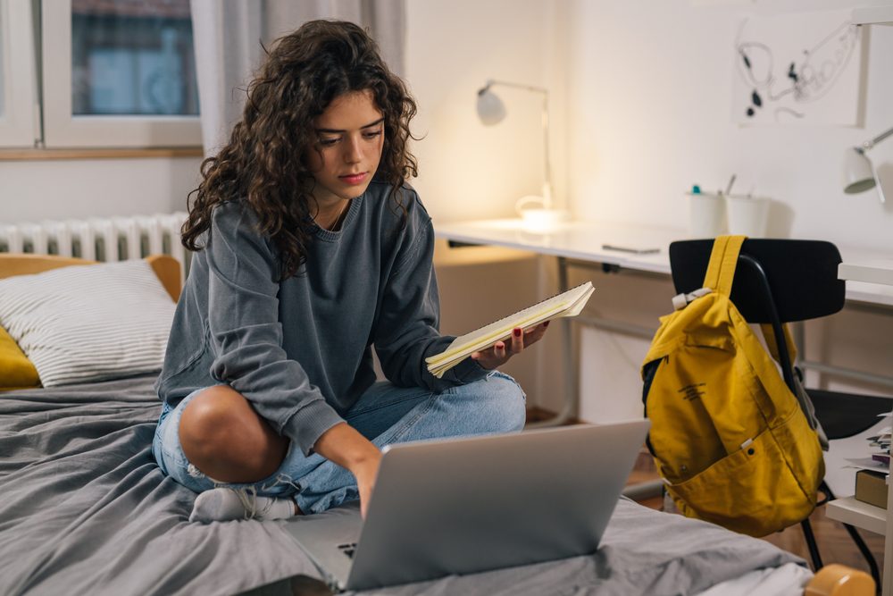 University student in a residence room putting on a backpack beside a smart speaker