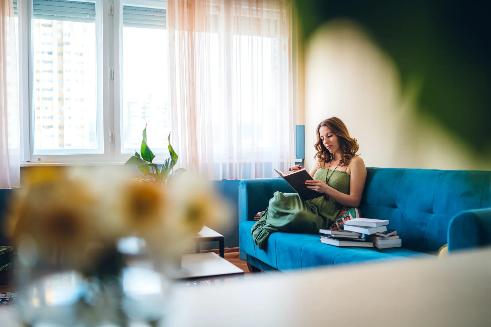 Woman writing in a journal on a couch in calm morning sunlight, tracking her week.