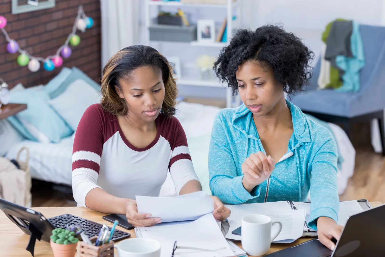 A parent and teenager sitting together at a desk with school papers and a laptop, weighing which type of assessment fits their situation.