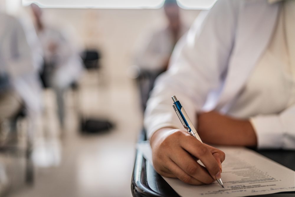 Student typing at a desk with a kitchen timer and a handwritten outline beside the laptop
