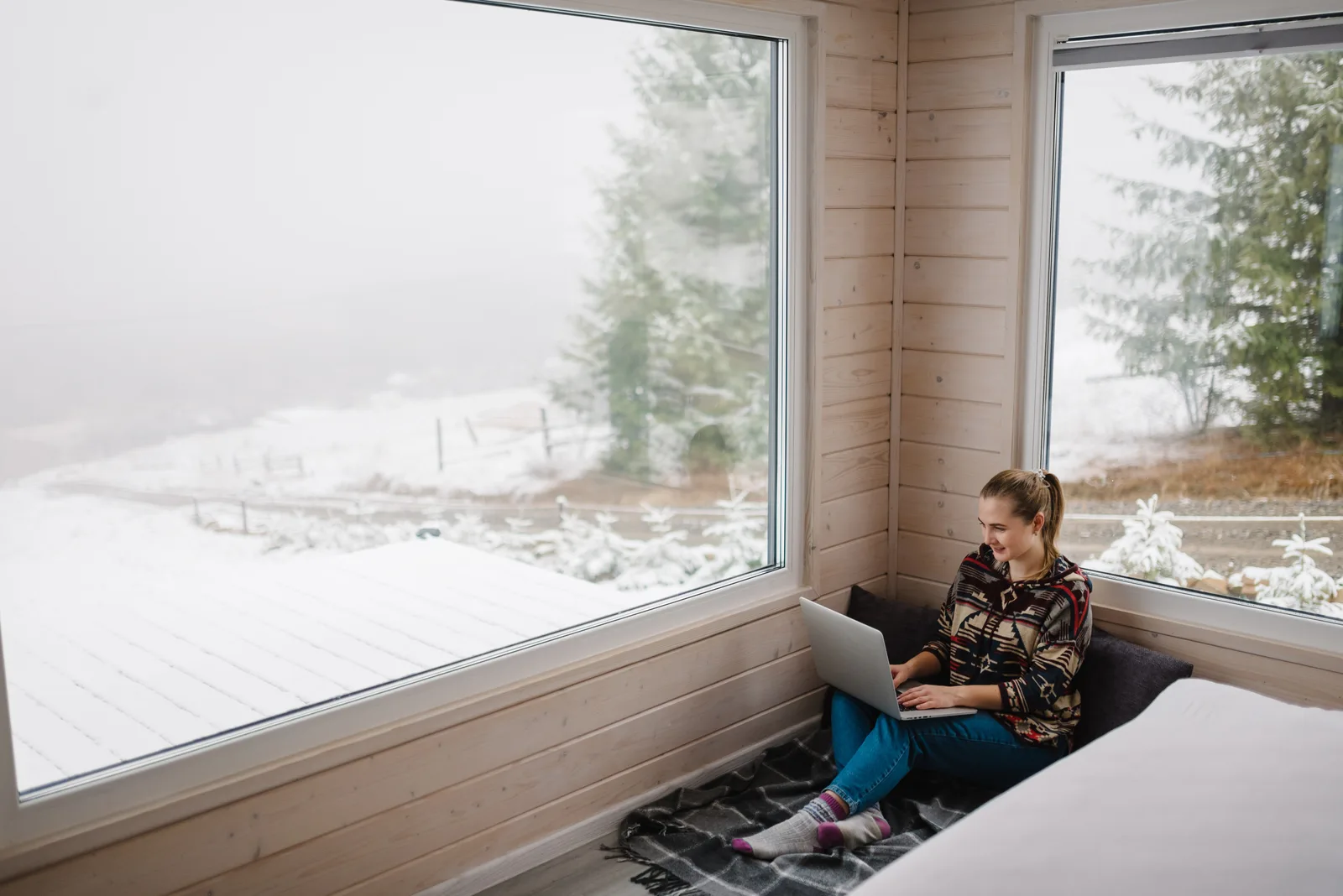 A woman with a coffee joins an online ADHD assessment on her laptop beside the window of a colourful St. John's row house