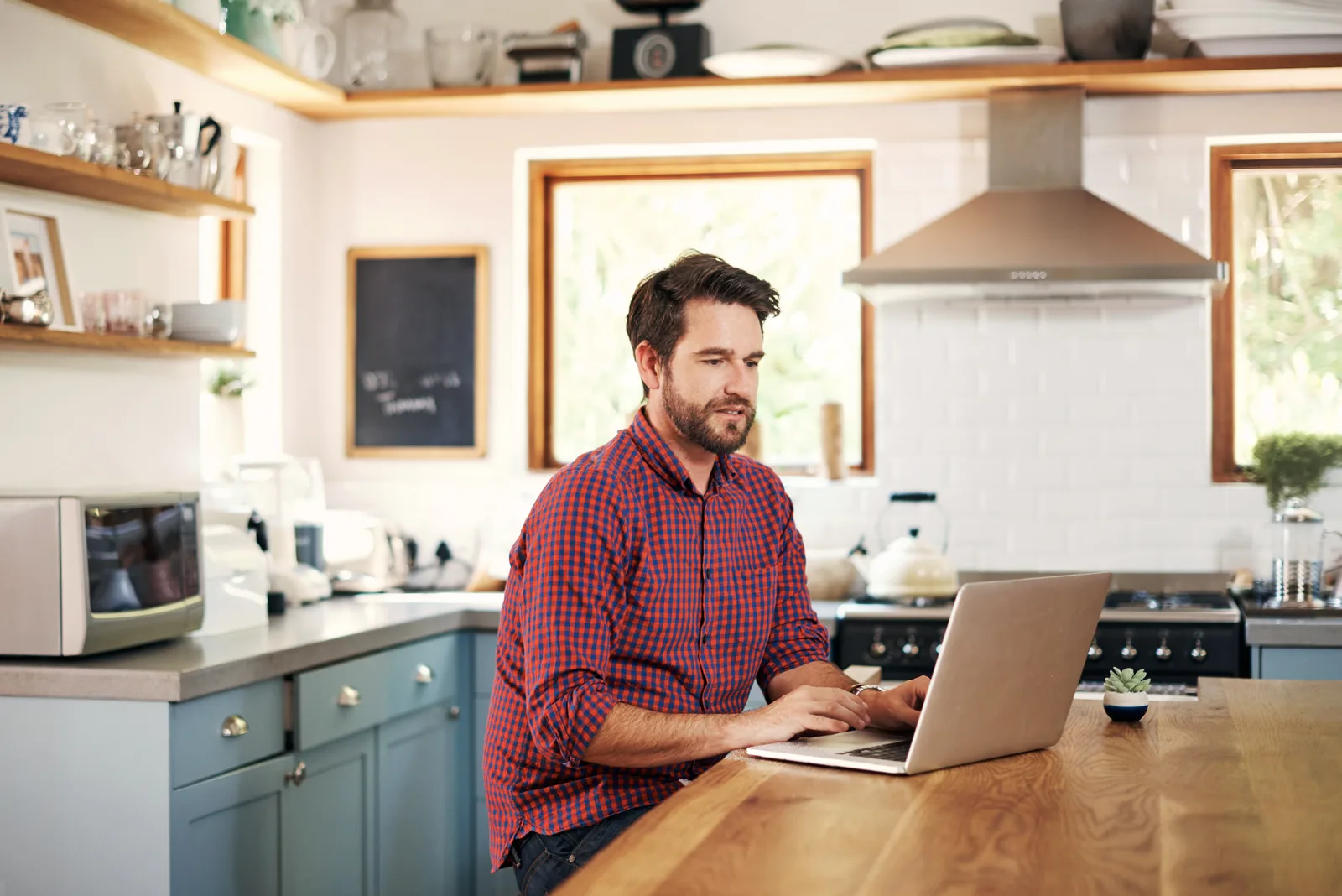 A woman at her prairie farmhouse kitchen table joins a video ADHD assessment on her laptop in morning light