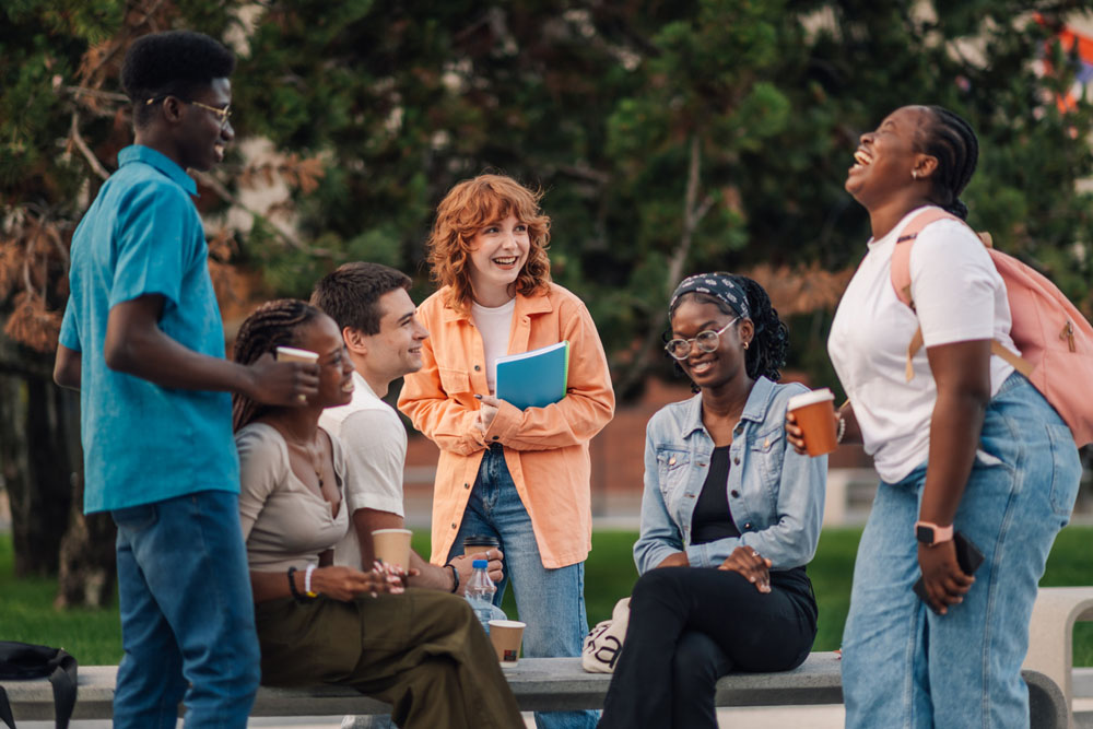 A diverse group of college students laughing and socializing outdoors, representing how ADHD students can build supportive friendships and relationships in university life.