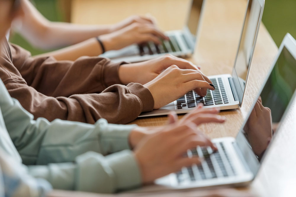 Students typing on laptops in a classroom, representing ADHD study hacks and exam preparation strategies to support focus, organization, and academic success.